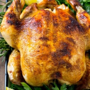 Slow cooker whole chicken with broiled crispy skin, garnished with lemon and herbs.